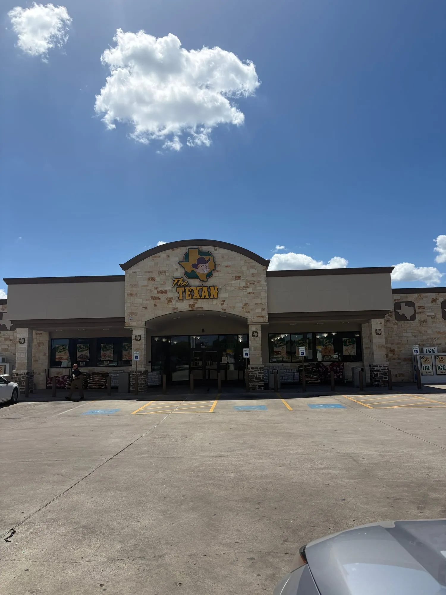 Limestone convenience store with an arched entrance and a sign reading The Texan over a cartoon cowboy on the shape of Texas